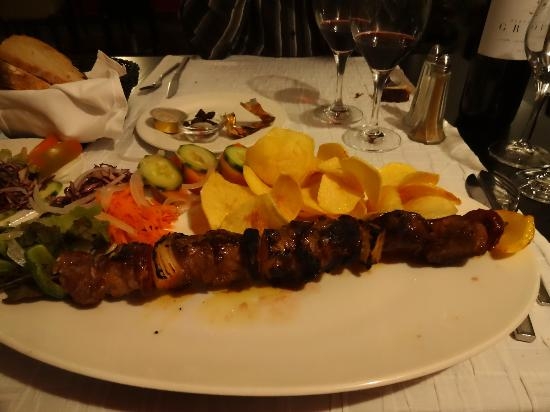 Brochette géante de viande avec accompagnements et verres de vin rouge
