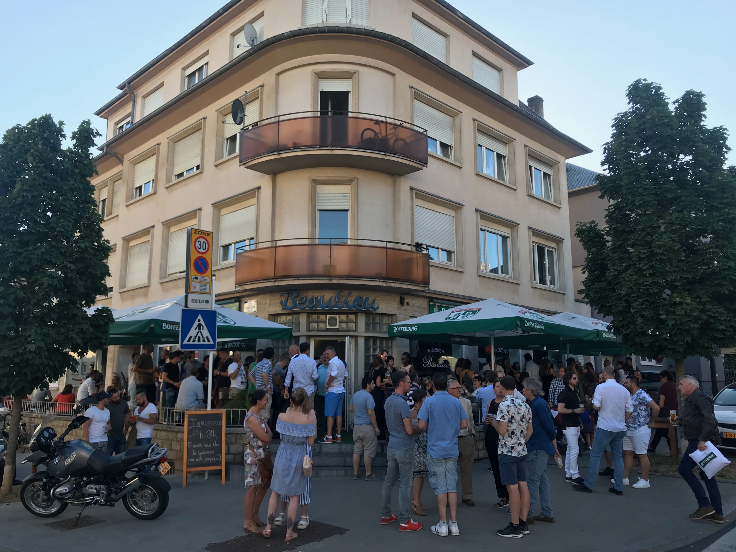 Ambiance en soirée devant la Brasserie Beaulieu, foule sous les parasols