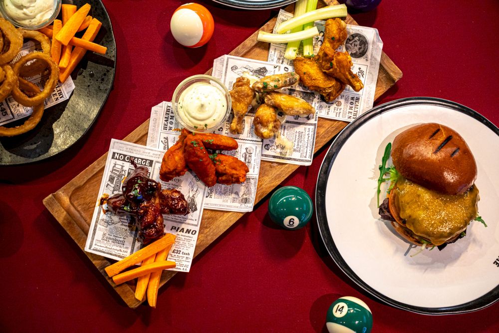 Wings et smash burger servis sur fond sombre à The Game